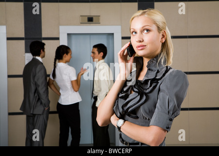 Photo de femme parlant au téléphone avec des personnes à l'arrière-plan Banque D'Images