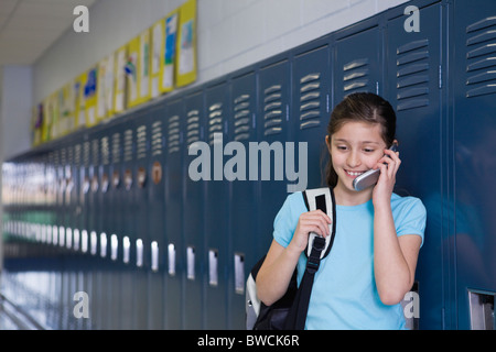 États-unis, Illinois, Metamora, Girl (8-9) debout à casiers en couloir d'école et talking on mobile phone Banque D'Images
