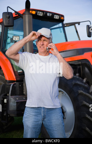 États-unis, Illinois, Metamora, agriculteur à l'aide de téléphone mobile par le tracteur Banque D'Images