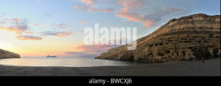 Coucher de soleil sur la plage de Matala, Crète, avec l'ère romaine tombes taillées dans la falaise sur la gauche. Banque D'Images