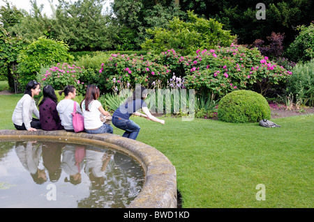 Les jeunes filles assise sur le bord d'un étang tout en prenant une photo d'eux en utilisant le retardateur sur l'appareil photo Banque D'Images