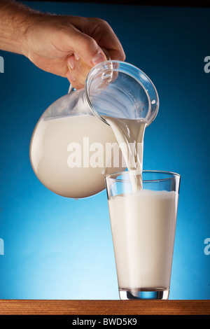 Le verre et le pot de lait sur un fond bleu. Banque D'Images