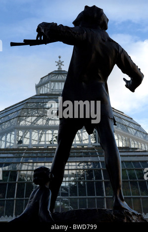 Statue de Peter Pan avec le Palm House à l'arrière-plan de Sefton Park, Liverpool. Banque D'Images