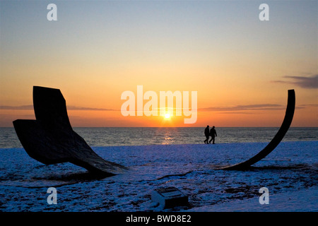 Silhouette de Passacaille de sculpture et des gens qui marchent sur la plage couverte de neige pendant le coucher du soleil. Brighton, UK JPH0272 Banque D'Images