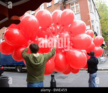 Hommes portant des ballons rouges Banque D'Images