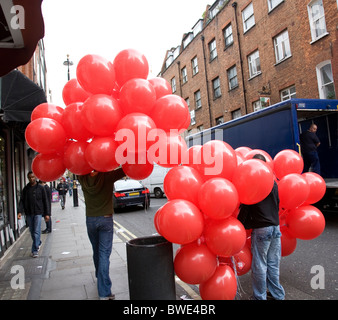 Hommes portant des ballons rouges Banque D'Images