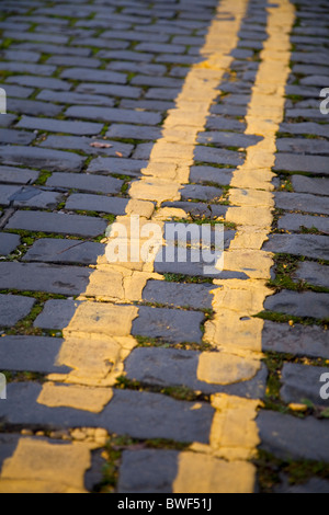 Les lignes jaunes indiquant double restriction parking interdit dans une rue pavée road Banque D'Images