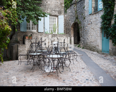 Des chaises en métal d'un Vaison la Romaine cafe empilés dans la rue, tandis que le café est fermé Banque D'Images