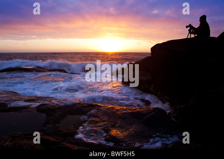 Un photograper prendre des photos du coucher de soleil sur l'île de Runde, Norvège Banque D'Images