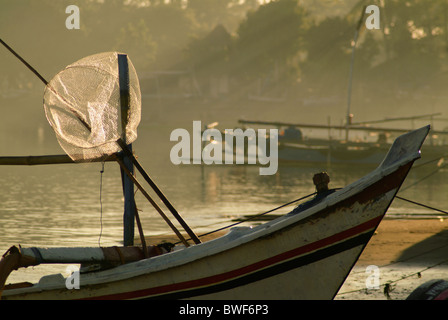 Dans la baie du village de pêcheurs de Pemuteran, Bali, les bateaux de pêche restent ancrées en attente de sortir dans la nuit pour la pêche. Banque D'Images