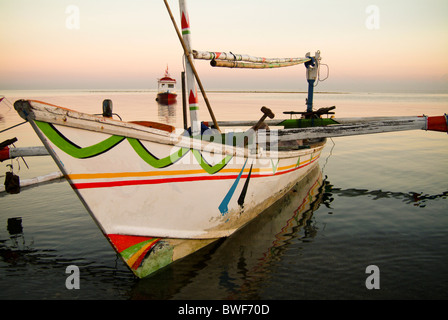 Un bateau de pêche balinaise, appelé un Jukung, est une pirogue pirogue peints dans des couleurs traditionnelles, équipé d'une voile. Banque D'Images