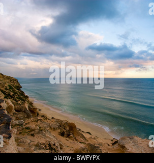 Rose doux nuages reflétée dans la mer bleu-vert, la pluie qui tombe dans les falaises de sable à distance en premier plan Wolfgat Nature Reserve False Banque D'Images