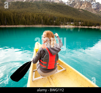 Une femme heureuse en canoë sur un lac glaciaire claire Banque D'Images