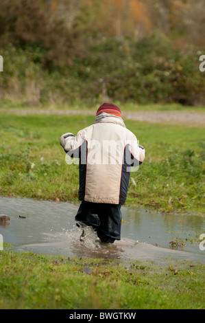 Un garçon jouant dans une flaque de Conwy RSPB réserve. Banque D'Images