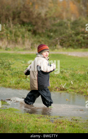 Un garçon jouant dans une flaque de Conwy RSPB réserve. Banque D'Images