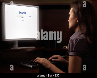 Jeune femme assise à un bureau informatique avec internet Moteur de recherche sur l'affichage Banque D'Images