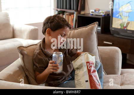 Quatre-année-vieux garçon mexico-mange de croustilles et de boissons gazeuses sips dans le salon à son domicile à Austin, Texas Banque D'Images