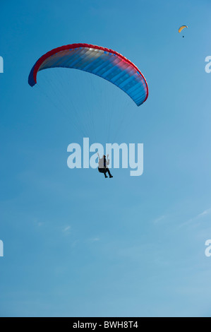 Parapentes viennent pour terres contre ciel bleu clair. Banque D'Images