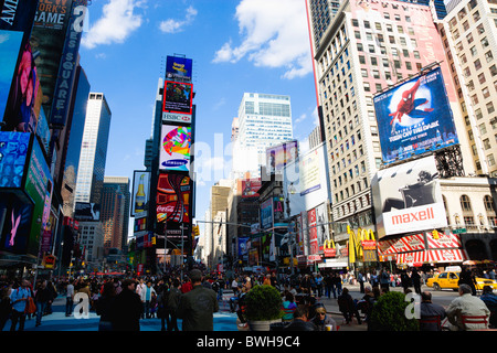 USA, New York, Manhattan, personnes marchant dans Times Square ci-dessous les bâtiments avec la publicité sur grands écrans vidéo Banque D'Images