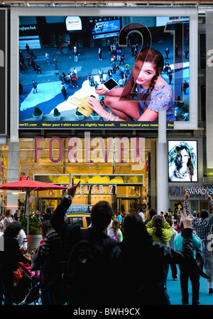 USA, New York, Manhattan, Personnes, gesticulant, à la recherche d'eux-mêmes en un géant live TV video en temps réel sur l'écran LED à Times Square