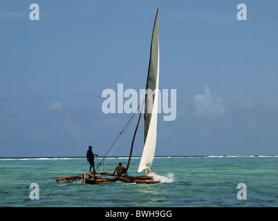 Bateau de pêche ou outrigger local (ngalawa dhow) voile sur Zanzibar Nungwi avec un homme d'équipage debout sur outrigger pour équilibrer la verticale du mât et voile Banque D'Images