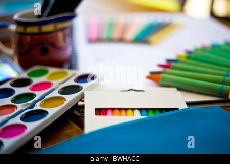Un assortiment de l'arrêt - Crayons de couleur, peinture, papier et crayons Posé sur bureau scolaire avec selective focus Banque D'Images