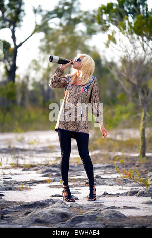 Young blonde woman boire du vin de la bouteille dans l'outback australien, pays Banque D'Images