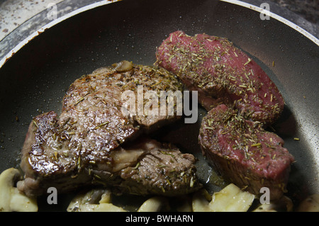 Moyen et la cuisson steak rare - 3 minutes de chaque côté pour les moyennes, 1 minutes chacun pour rare, cuits ensemble. Banque D'Images