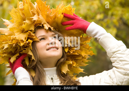 Portrait of smiling young woman touching guirlande de feuilles d'érable Banque D'Images