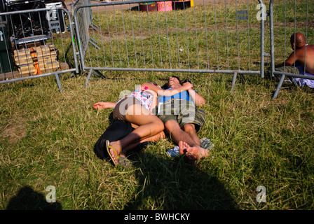 Couple allongé sur l'herbe dans la chaleur à Glastonbury Festival 2010 Banque D'Images