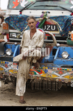 Mécanicien automobile appuyé contre un camion, Karachi, Pakistan Banque D'Images