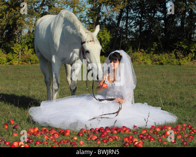 La mariée et son cheval sur les champs d'apple Banque D'Images