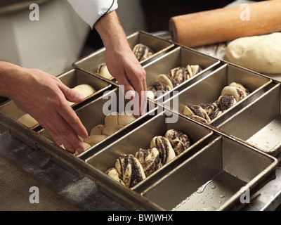 Libre de boulangers mains mettre du pain dans une plaque à pâtisserie Banque D'Images