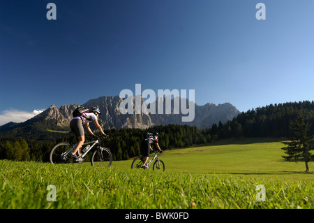Jeune couple riding mountain bikes sous le ciel bleu, le Tyrol du Sud, Italie, Europe Banque D'Images