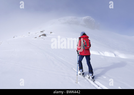 Femme ski de montagne un croissant, des rochers qui apparaissent à travers un fogbank en arrière-plan, Schusterkogel, Saalbach-Hin Banque D'Images