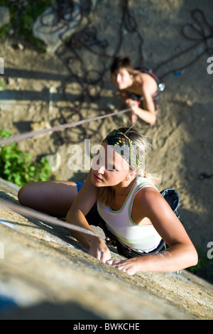 La photo d'une femme d'escalade sur le rocher et l'homme debout par son Banque D'Images