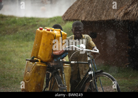 Les habitants de vélo enfant Vélo garçon le transport de l'eau de pluie l'eau potable de l'Est de l'Ouganda Kisoro africaine un Banque D'Images