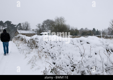 Homme marchant le long d'une route couverte de neige dans un paysage d'hiver Banque D'Images