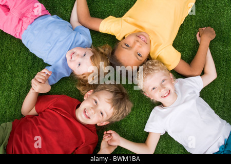 Photo de groupe d'enfants allongés sur l'herbe ensemble Banque D'Images