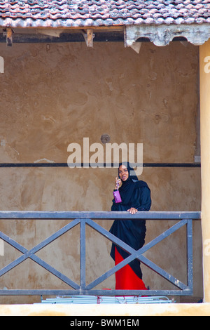 Femme musulmane sur un téléphone mobile à Lamu Fort ou Fumo Madi ibn Abi Bakr, l'île de Lamu, Kenya Banque D'Images