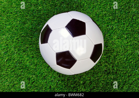 Un damier noir et blanc ou de football en cuir ballon de soccer sur l'herbe. Banque D'Images