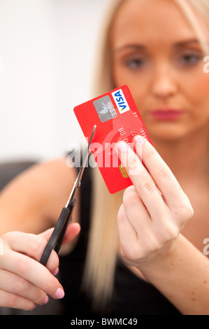 Jeune femme blonde de couper sa carte de crédit. Banque D'Images