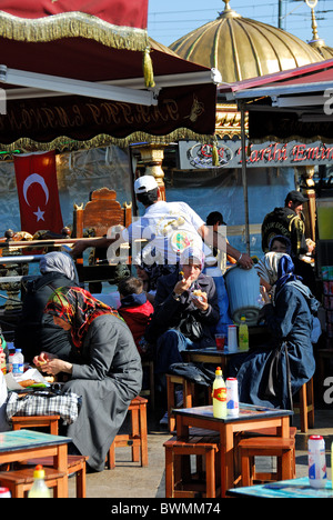 ISTANBUL, TURQUIE. Les jeunes femmes de manger balik ekmek (sandwichs) maquereau par la Corne d'or dans le district d'Eminonu. L'automne 2010. Banque D'Images