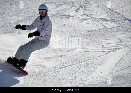 Les femmes d'âge moyen snowboarder portant casque et lunettes de neige dans la poudreuse sur colline - tourné à Livigno, Alpes Italiennes Banque D'Images