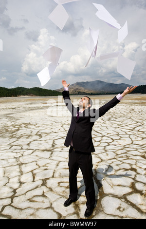 Photo de portrait debout sur un sol sec et jeter feuilles vers le haut Banque D'Images