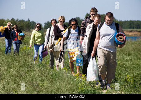 Droit de la file d'attente de touristes marchant dans l'herbe bien verte alors que sur l'extérieur voyage Banque D'Images