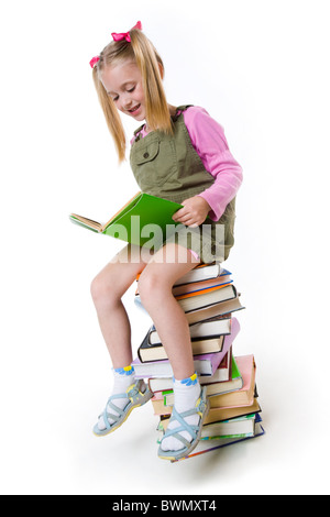 Image de lycéenne assis sur le tas de livres et de la lecture l'un d'eux Banque D'Images