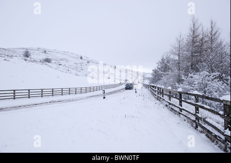 Un véhicule circule le long d'une route couverte de neige sur Ilkley Moor. Banque D'Images