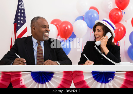 États-unis, Illinois, Metamora souriant, l'homme et la femme à la table de scrutin, des ballons rouges et bleus en arrière-plan Banque D'Images