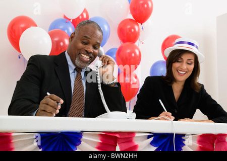 États-unis, Illinois, Metamora souriant, l'homme et la femme à la table de scrutin, des ballons rouges et bleus en arrière-plan Banque D'Images